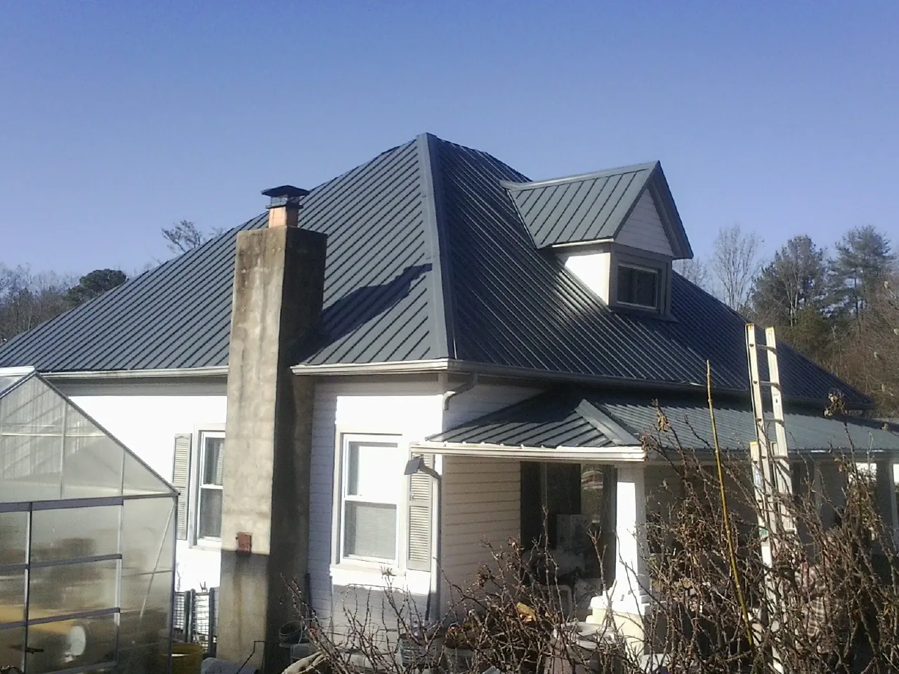 Dark blue standing seam metal roof on a white farmhouse with dormer — Slate & Tile Roof Repair by Roofing Brothers in Willimantic