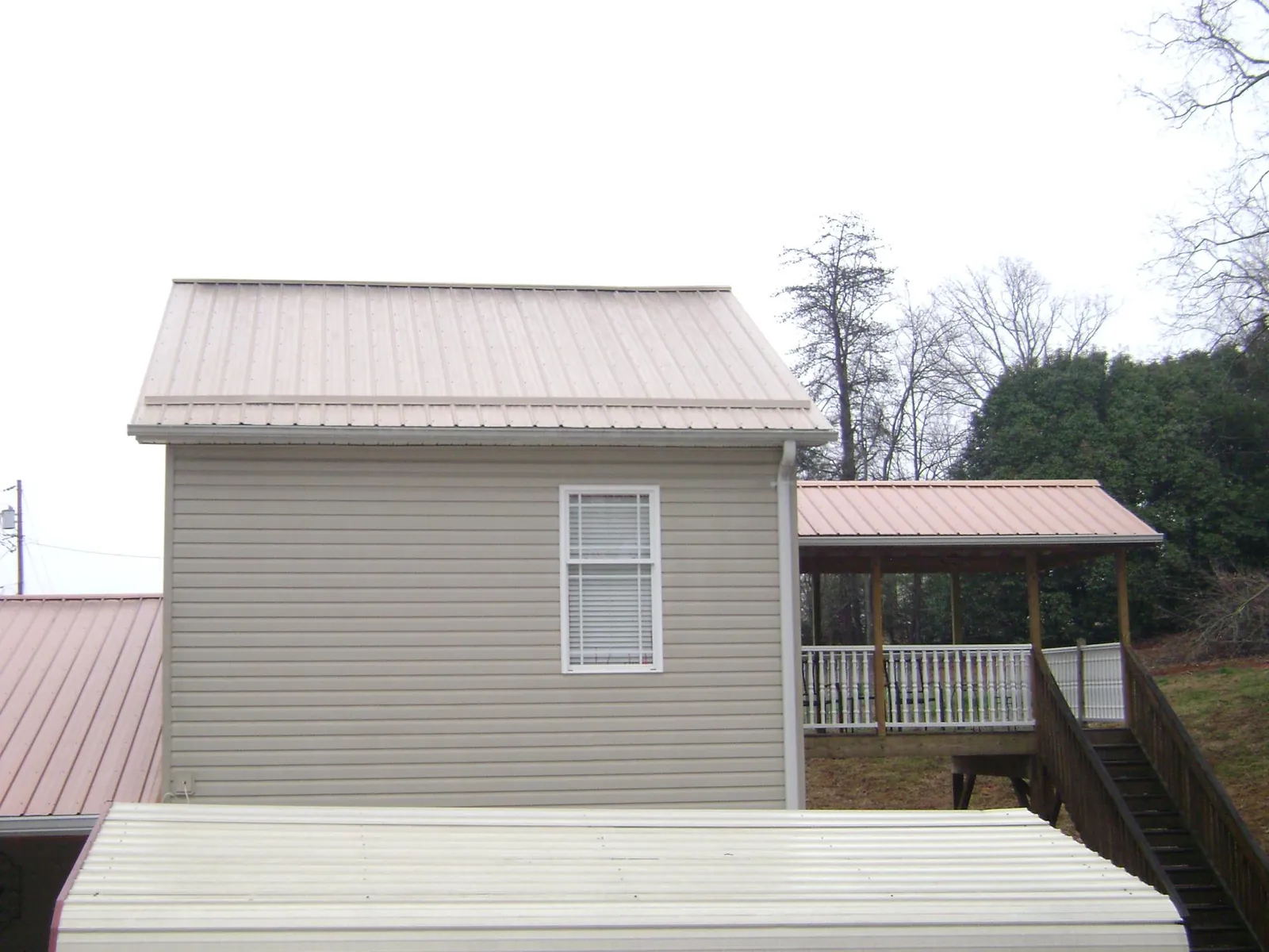 Tan metal roofs on a two story addition and attached porch, from a Roof Replacement job in Willimantic