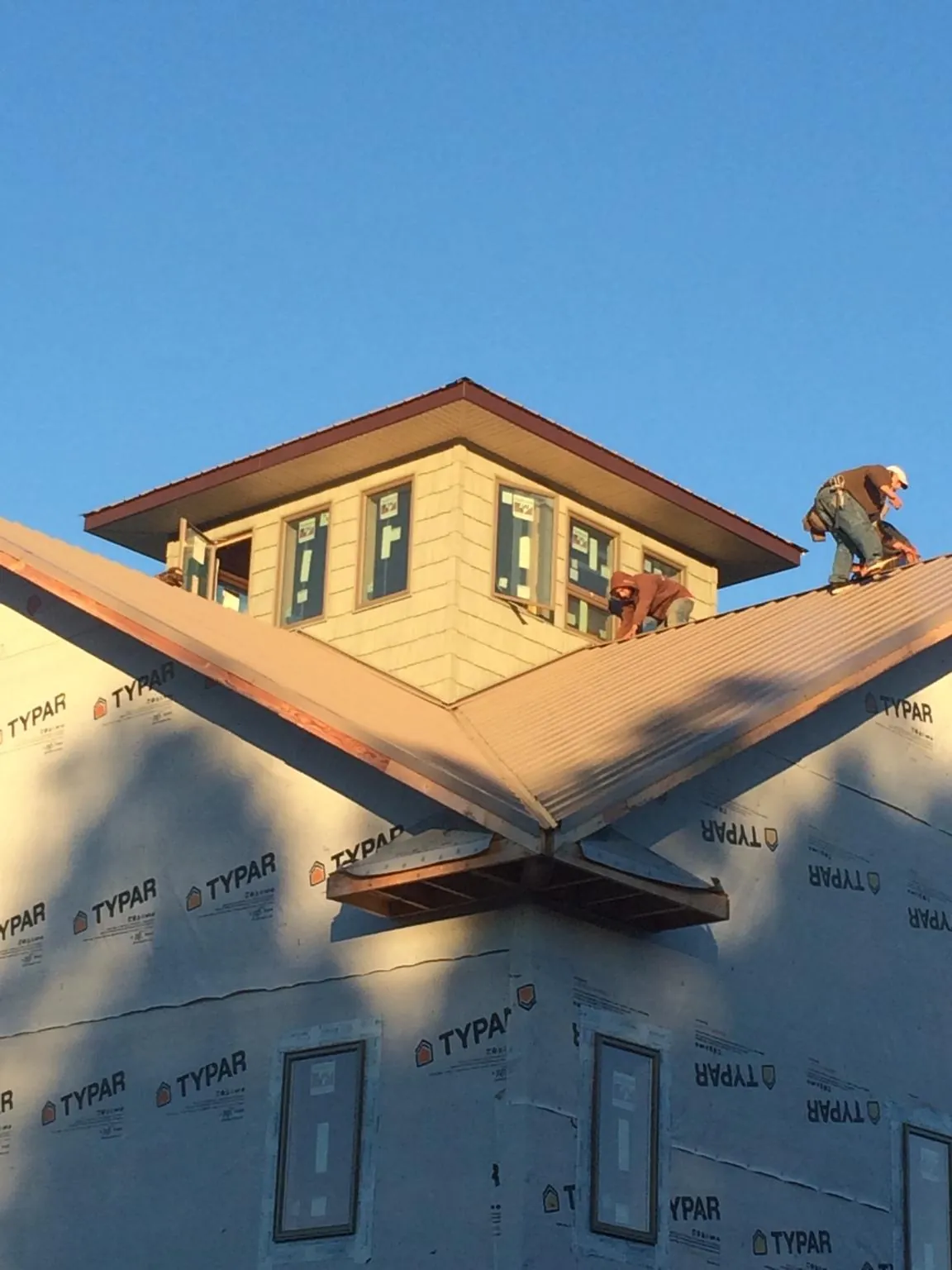 Roofers working around a rooftop cupola on a new metal roof at sunset — Roof Waterproofing in Willimantic by Roofing Brothers
